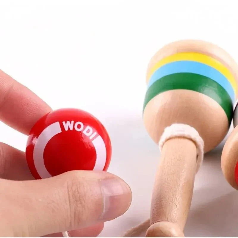 Hand holding a red throw ball connected to a striped wooden skill cup toy