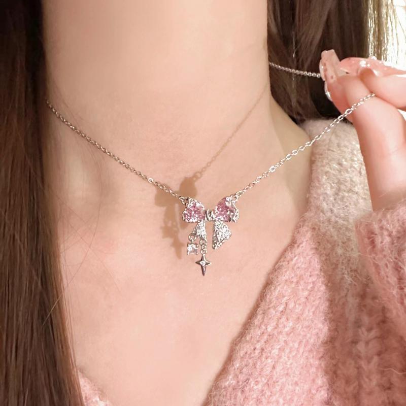 Bow pendant necklace on model: pink sparkle bow with dangling star and heart charms