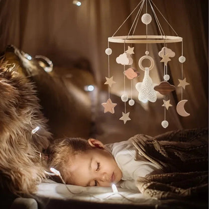 Wooden baby crib mobile with cloud, star, and heart hanging charms above sleeping baby