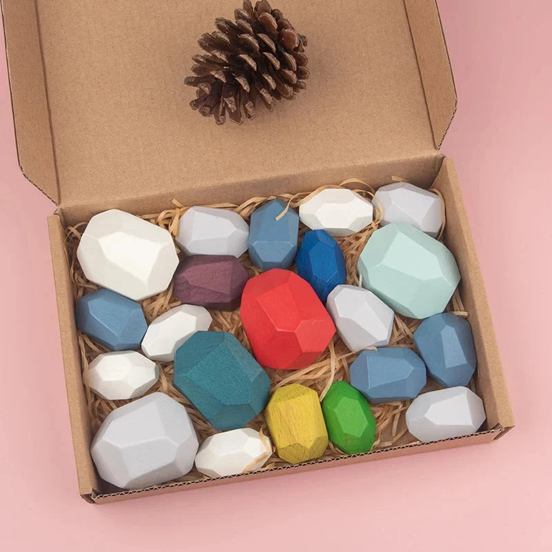 Wooden stacking rocks in open box, faceted hexagon pieces in white, blue, red, and green