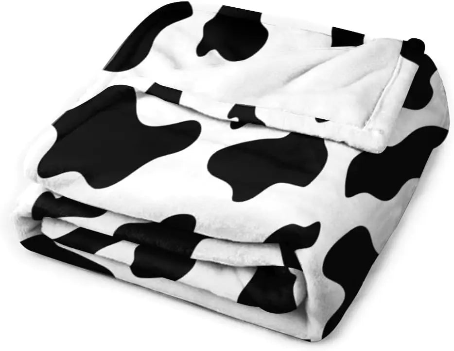 Black-and-white cow print flannel blanket, neatly folded stack