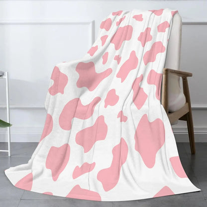 Cow print flannel blanket in pink and white, draped over the floor