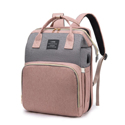 Mauve and gray diaper backpack with top handle, front zipper panel, and side straps