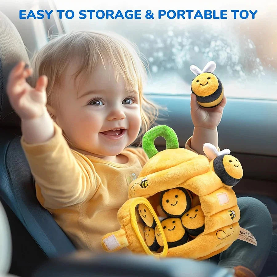 Soft yellow beehive sensory toy with smiling bee faces, held by baby in a car seat