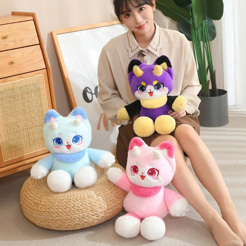 Purple dragon cat plush on lap with light blue and pink plush toys beside it
