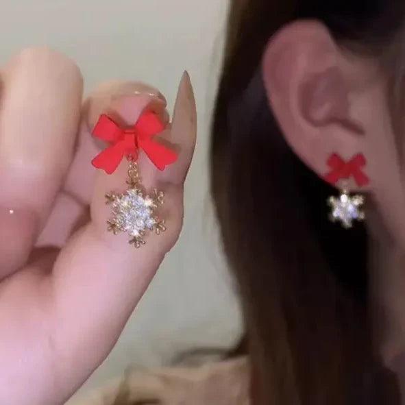 Red bow and silver snowflake charm earrings on gold-tone hooks