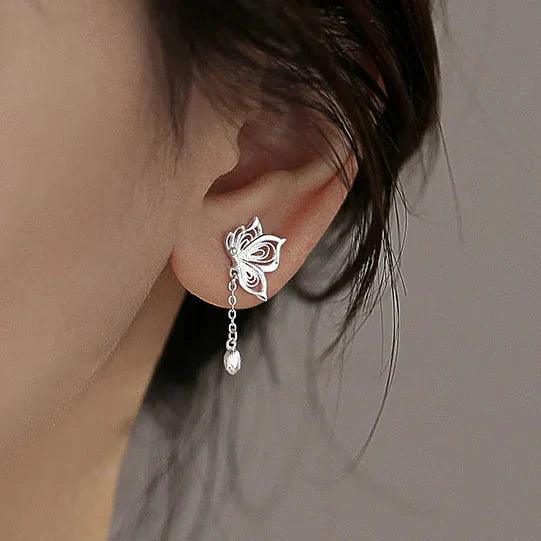 Silver butterfly stud earrings worn with dangling chain and teardrop charms