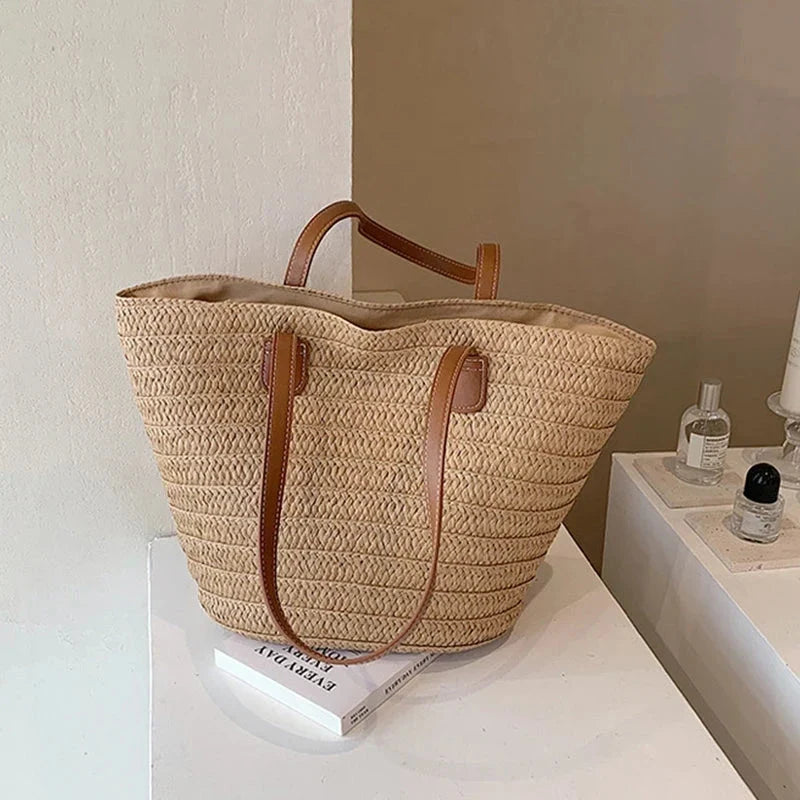 Large woven straw tote bag with brown faux-leather handles and top lining