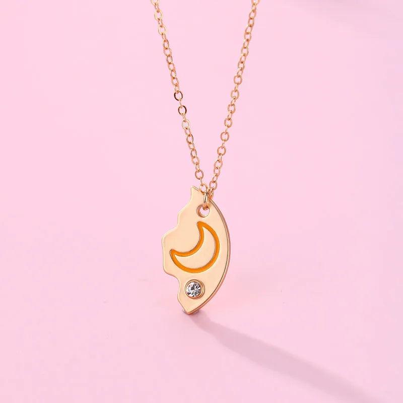 Moon crest pendant necklace with orange crescent, rhinestone accents, and gold chain