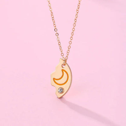 Moon crest pendant necklace with orange crescent, rhinestone accents, and gold chain