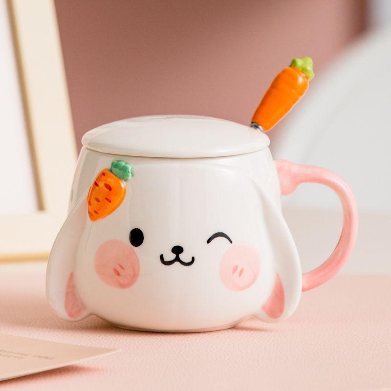 Rabbit ceramic lidded mug with pink handle, carrot spoon on the rim, bunny face.