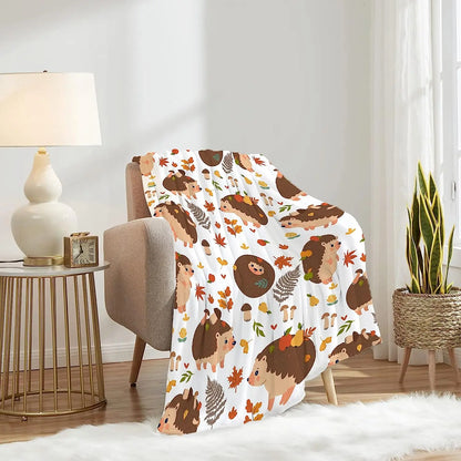 Hedgehog and autumn leaf blanket, white with brown hedgehogs and orange leaves, draped on chair