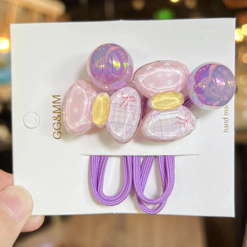 Purple elastic hair ties with translucent heart and bunny charms on a card backing