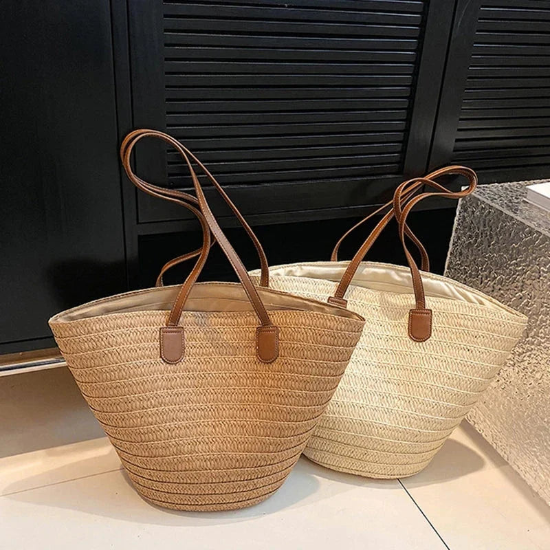 Two woven straw tote bags with brown faux-leather handles, one light and one tan