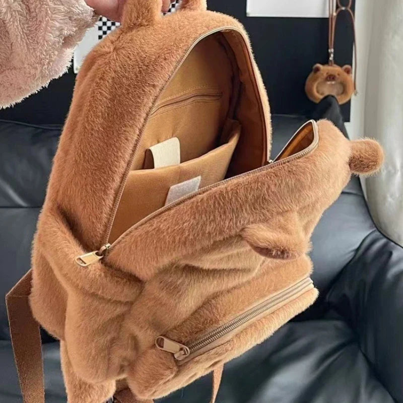 Tan capybara plush backpack with front zip pocket, open interior, and inner compartments