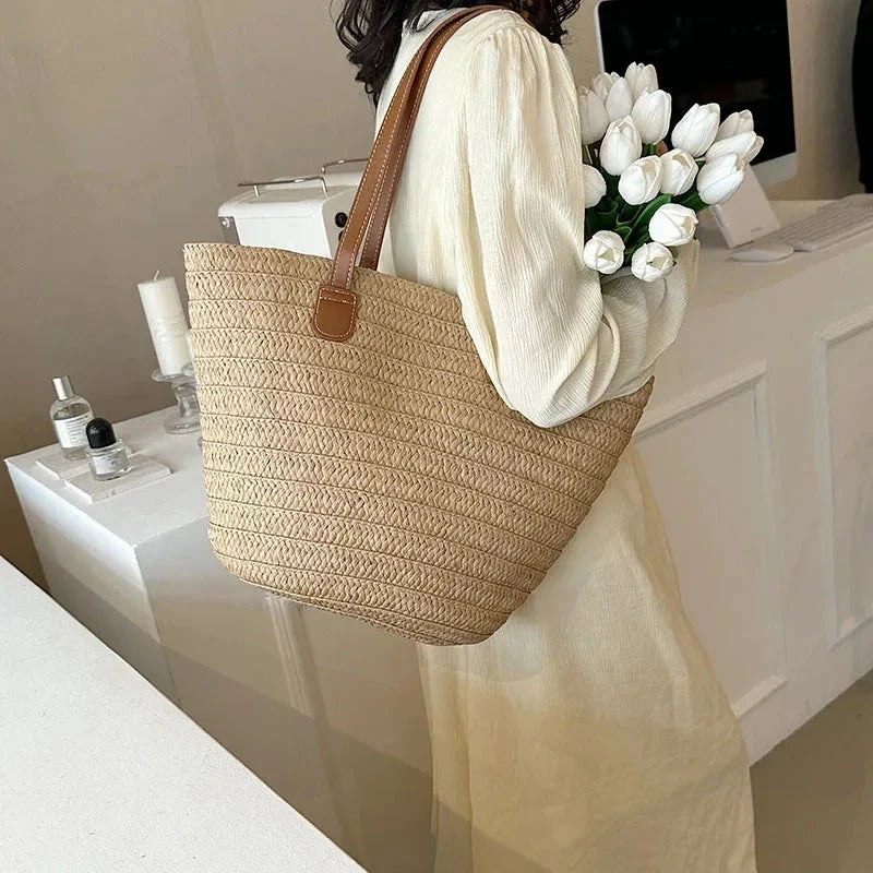 Large straw woven tote bag with brown handles and open top