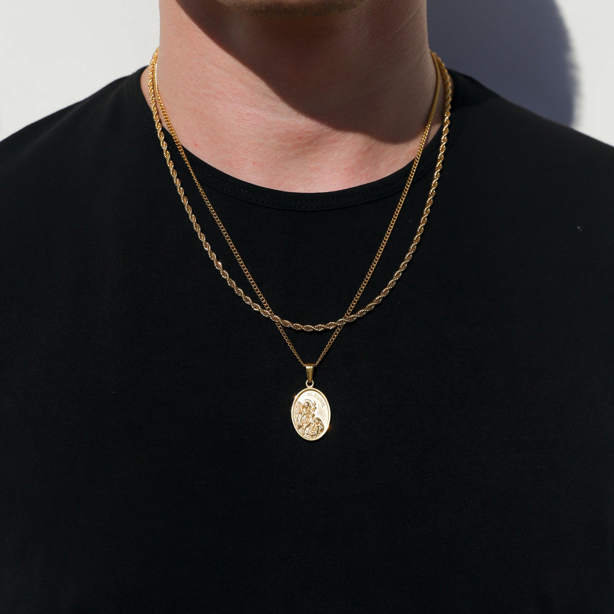 Gold tone layered chain necklace set with oval pendant and coin medallion