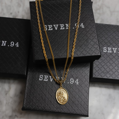 Gold layered chain necklace with oval pendant, shown with a branded gift box