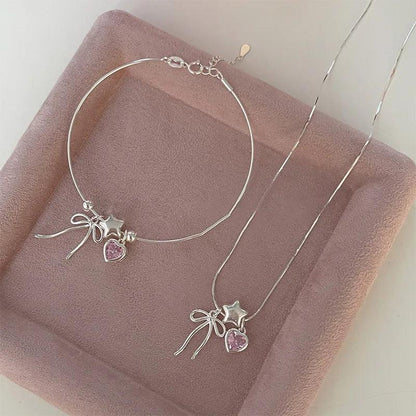 Silver necklace with star and bow charms and pink heart pendant accents