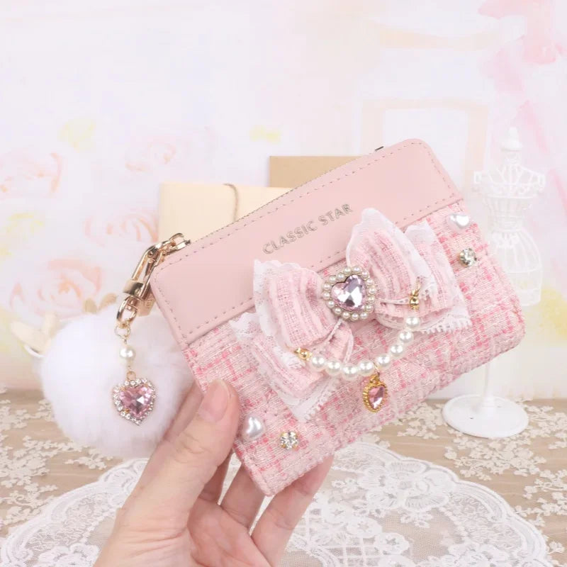 Pink quilted wallet with bow and heart charms, pearl trim, and gold-tone zipper