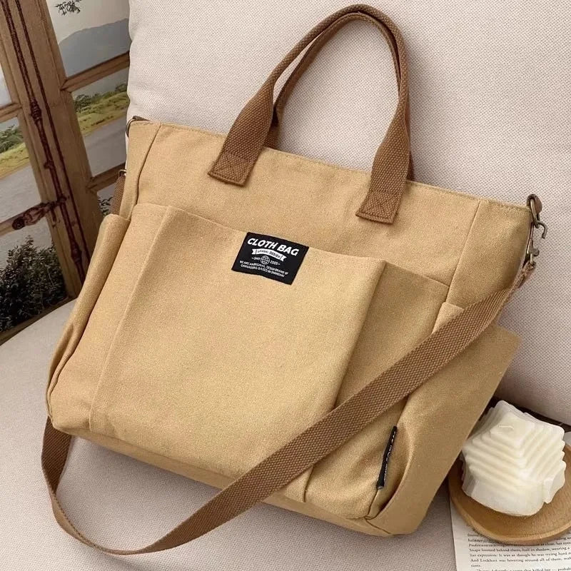 Khaki canvas tote bag with two handles and diagonal crossbody strap, front organizer pocket