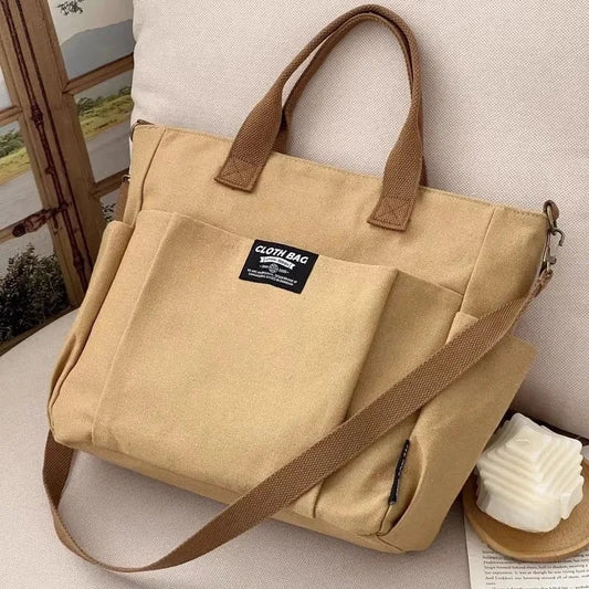Khaki canvas tote bag with two handles and diagonal crossbody strap, front organizer pocket