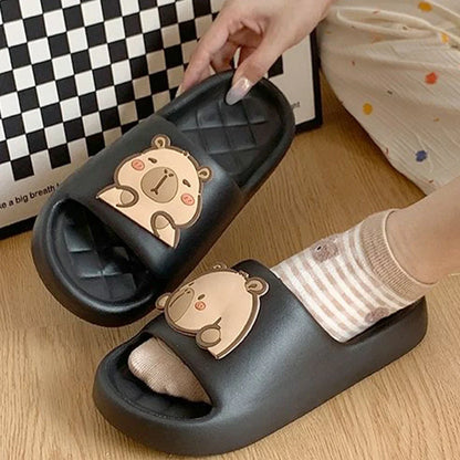 Black capybara slide sandals with quilted footbed and tan cartoon face patch.
