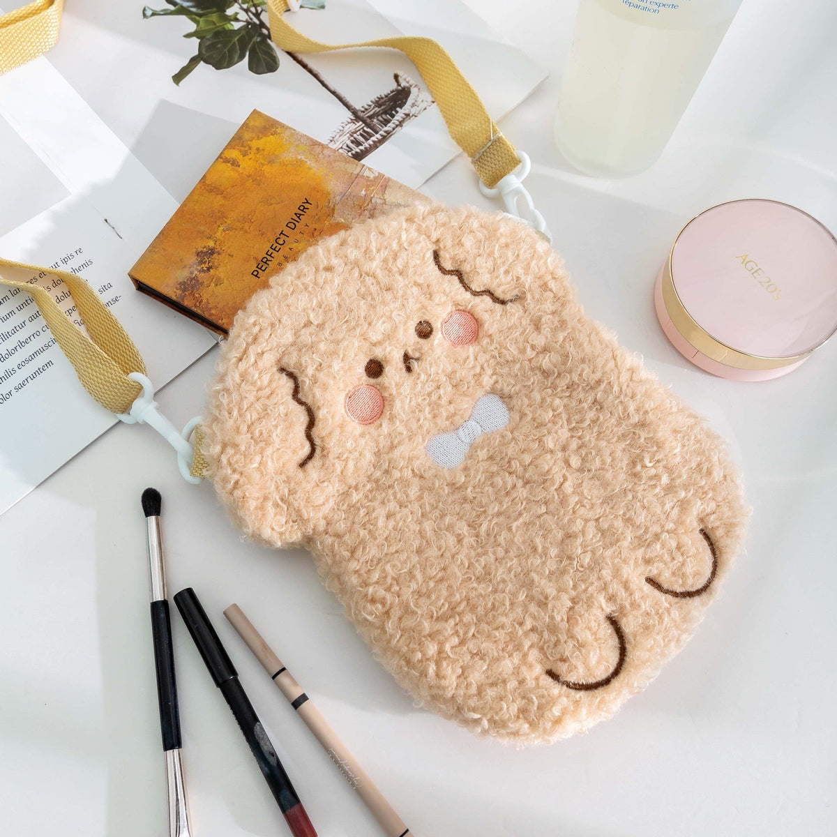 Tan plush bear crossbody bag with embroidered eyes and adjustable shoulder strap