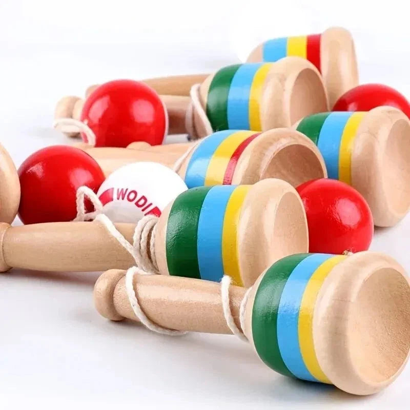 Close-up of striped wooden skill cup toys with red throw balls and strings