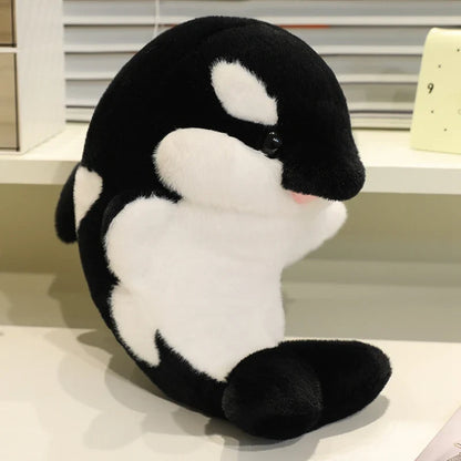 Black dolphin plush with white belly patch, curved body, embroidered eye and muzzle