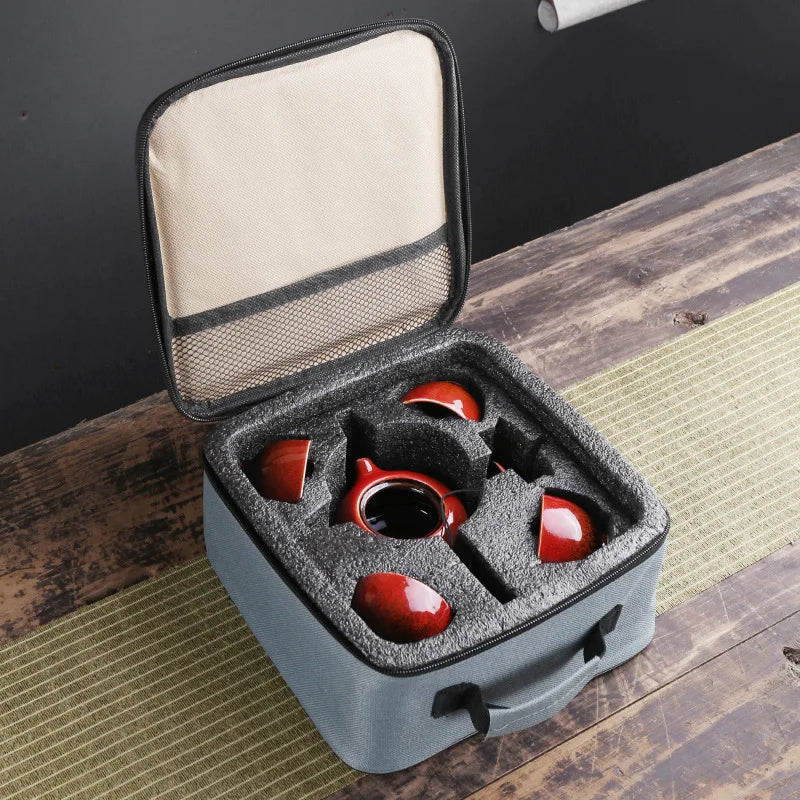 Portable tea set carrying case open with molded slots for red teapot, cup, and strainer