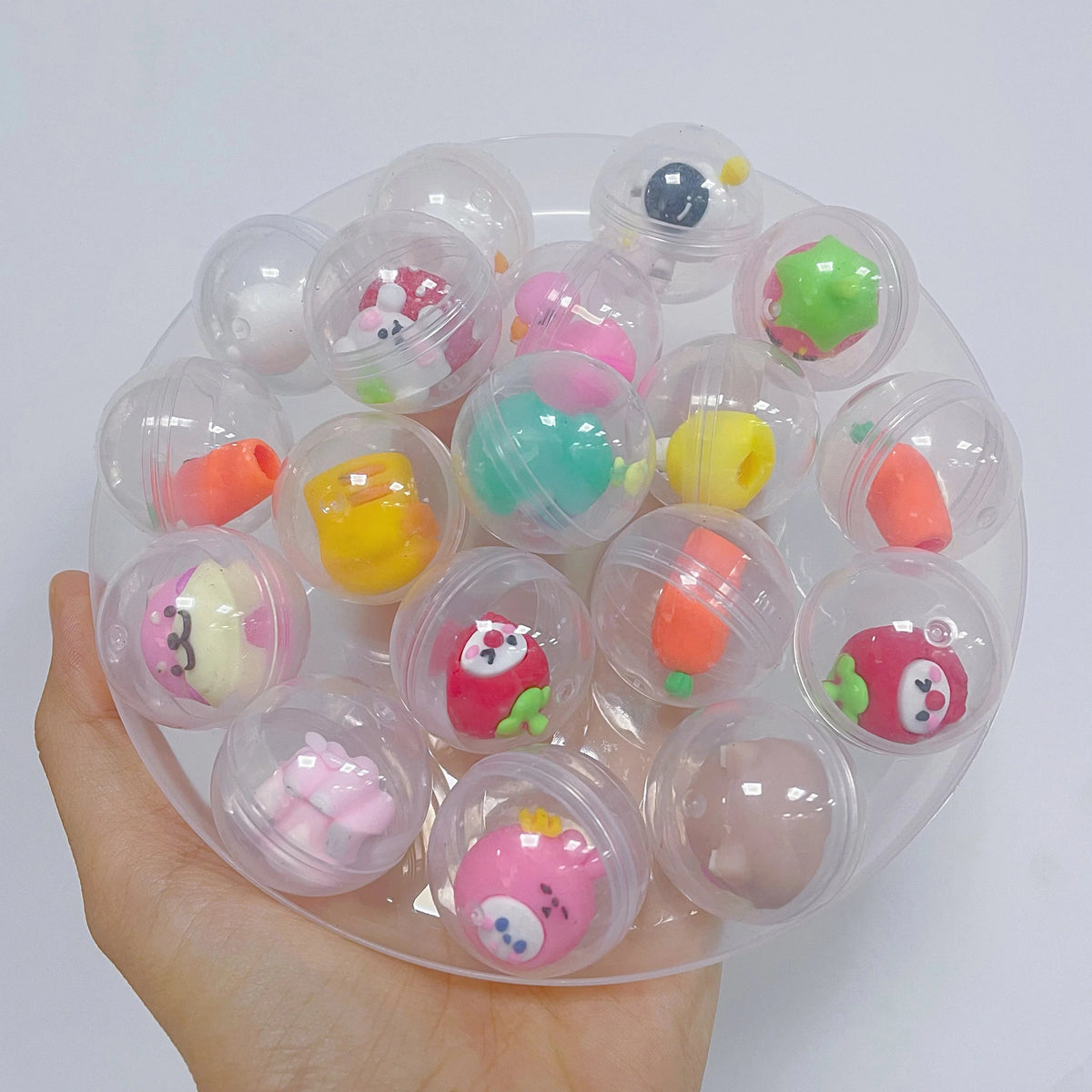 Hand holding a transparent plastic capsule egg with cute animal plush figures inside