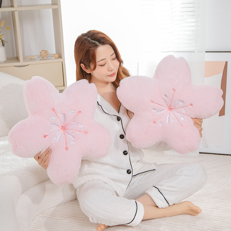 Pink cherry blossom plush pillows, two flower cushions held by person in white pajamas