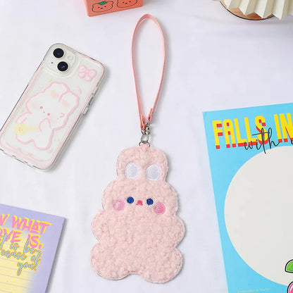Pink plush animal photo card sleeve with lanyard strap next to smartphone