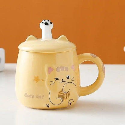 Yellow cat face lidded mug with paw prints, standing on a flat surface