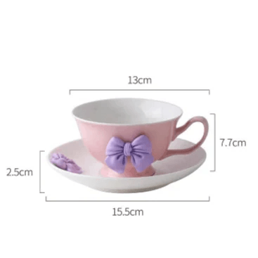 Pink teacup and saucer set with light purple bow decoration and right-side handle