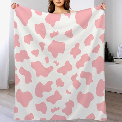 Cow print flannel blanket in pink and white, held up for display