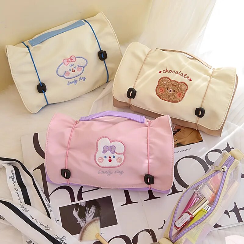 Kawaii roll-up travel makeup bag set with light beige, pink, and cream zip pouches