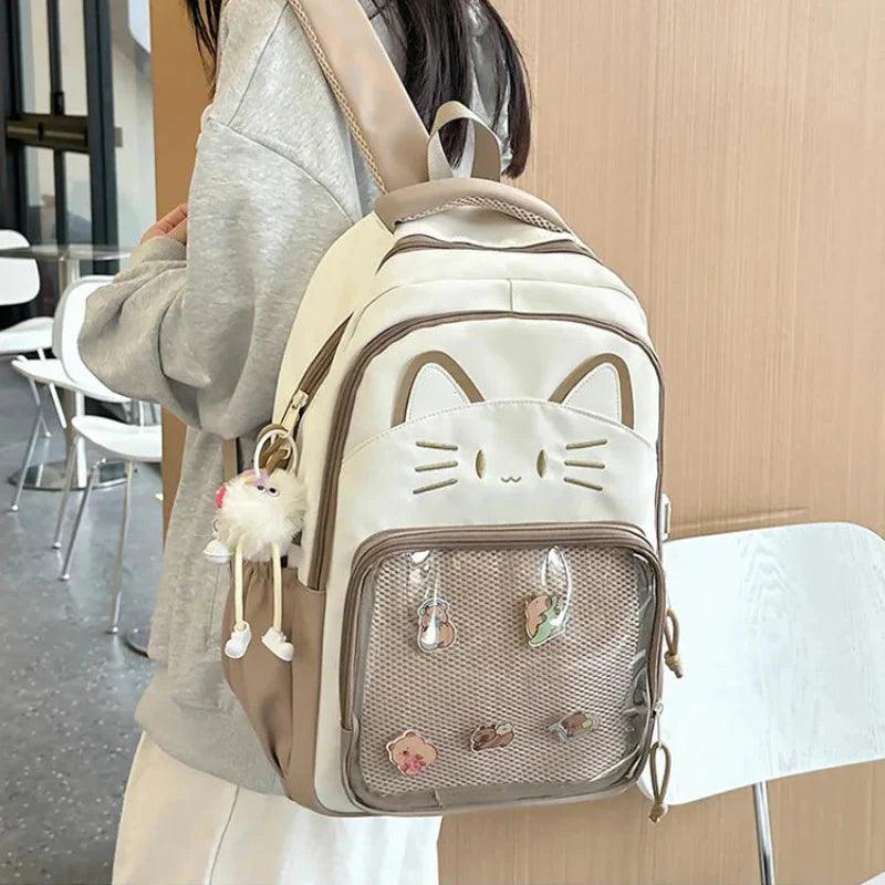 Cream mini cat-ear school backpack with mesh front pocket and dangling pom keychain
