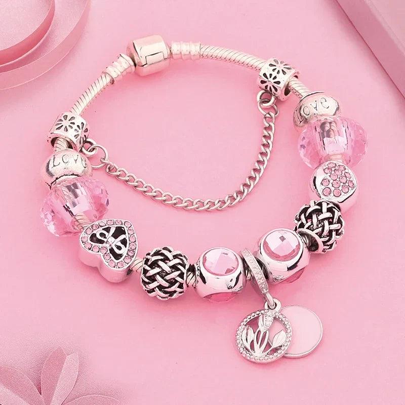 Pink charm bracelet with silver-tone beads, braided center charm, heart locket, flower dangles