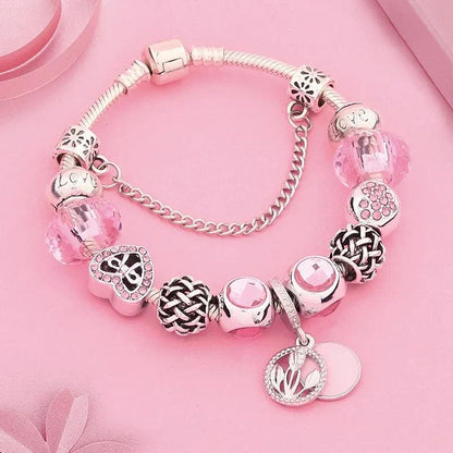 Pink charm bracelet with silver-tone beads, braided center charm, heart locket, flower dangles