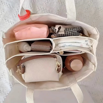 Cream canvas tote bag interior with multiple compartments and small zip pockets