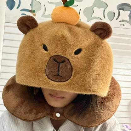 Capybara plush neck pillow hat in tan and brown with stitched face and nose.