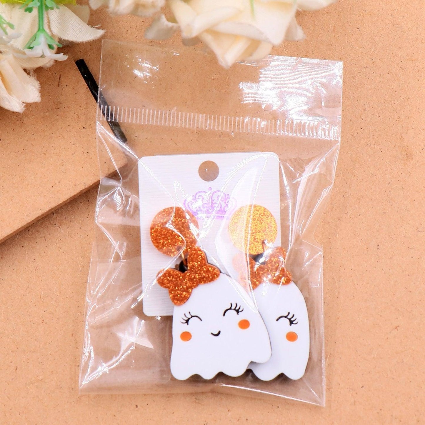 Pair of Halloween ghost face earrings on card, glitter orange crown and bow with white drops