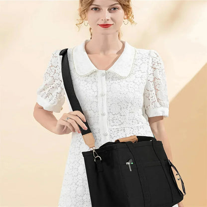 Black canvas large tote bag with multiple interior pockets and adjustable crossbody strap