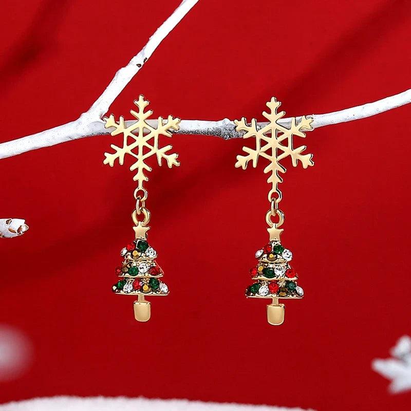 Drop earrings with two gold snowflake charms and small decorated Christmas tree dangles