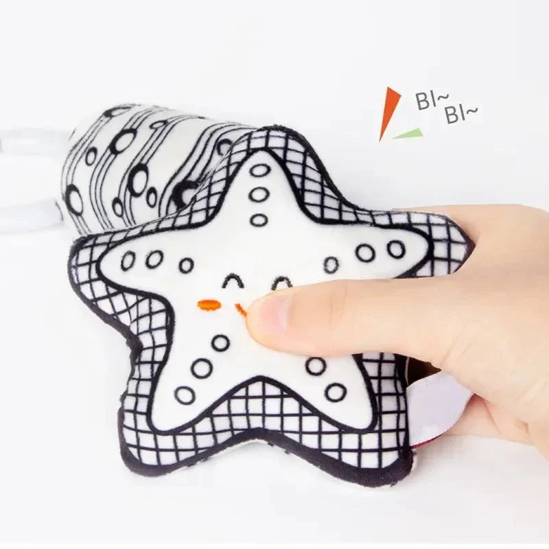 Star-shaped plush baby rattler with black-and-white patterned fabric and hand grip