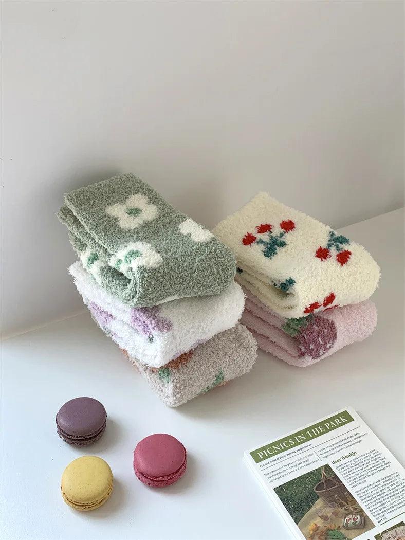 Plush sleeping socks stacked in green, cream, and pink with small fruit motifs