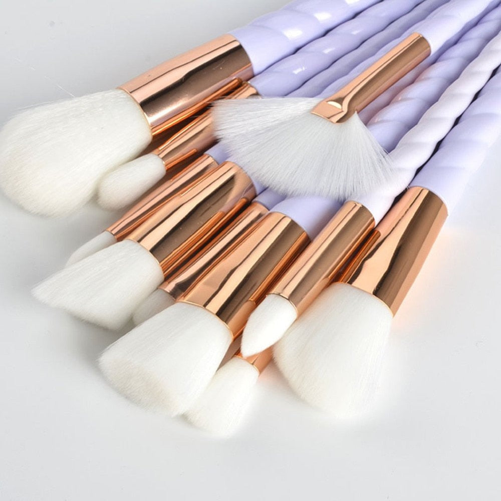 Makeup brushes close-up: white bristles with rose-gold caps and light lavender spiral handles