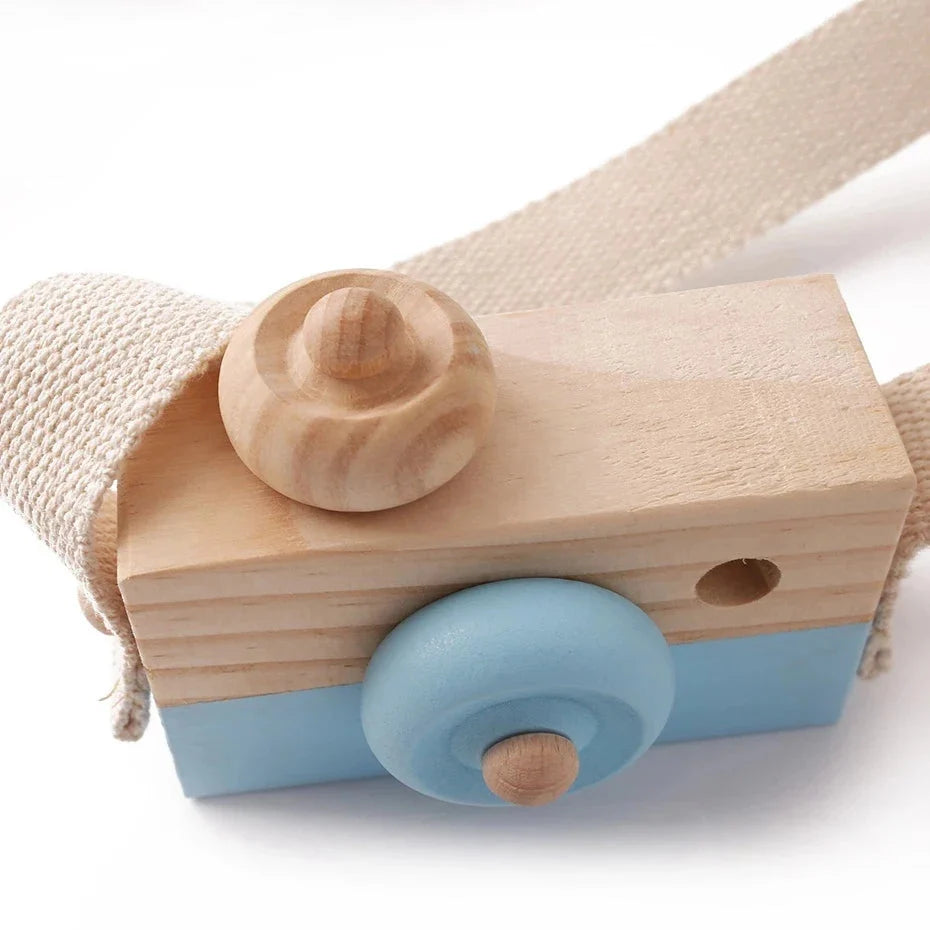 Wooden camera pendant toy with beige strap, light wood top, and blue circular lens